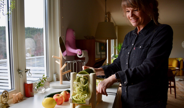 Kvinne lager Squash-spagetti med en grønsaksstrimler