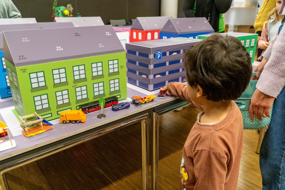 Barn bygger by med små hus og biler